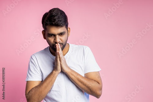 Portrait of handsome Indian guy standing on pink background