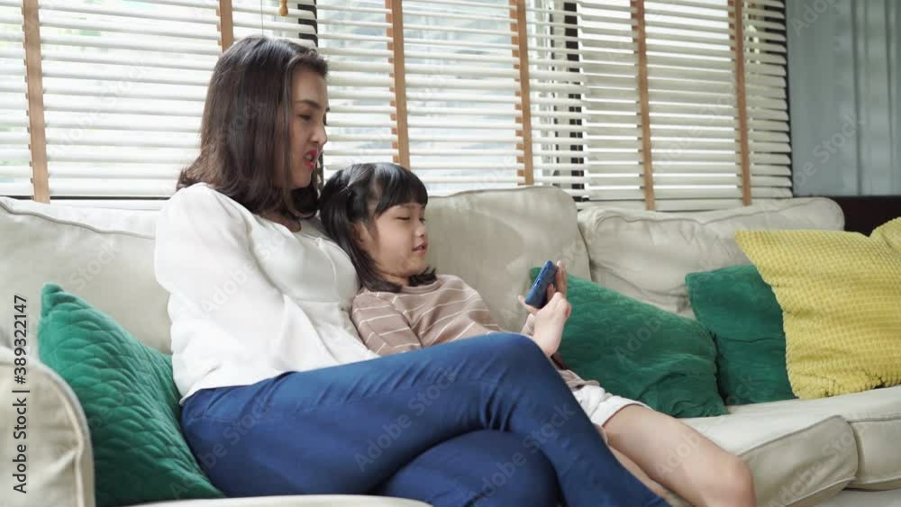 Asian family making a video call and waving at the caller with daughter in living room at home. Asian family making a video call and waving at the caller with daughter in living room at home.