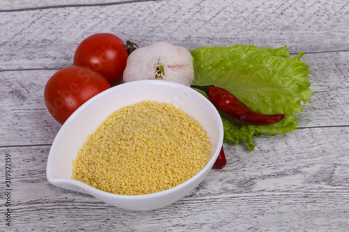 Raw couscous in the bowl served salad leaves, tomato and pepper photo