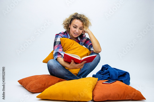 Girl sitting on the floor of a pillow reads a running book of thought interest photo