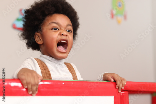 Photography African American boy with curly hair shouting while playing at the playground, k