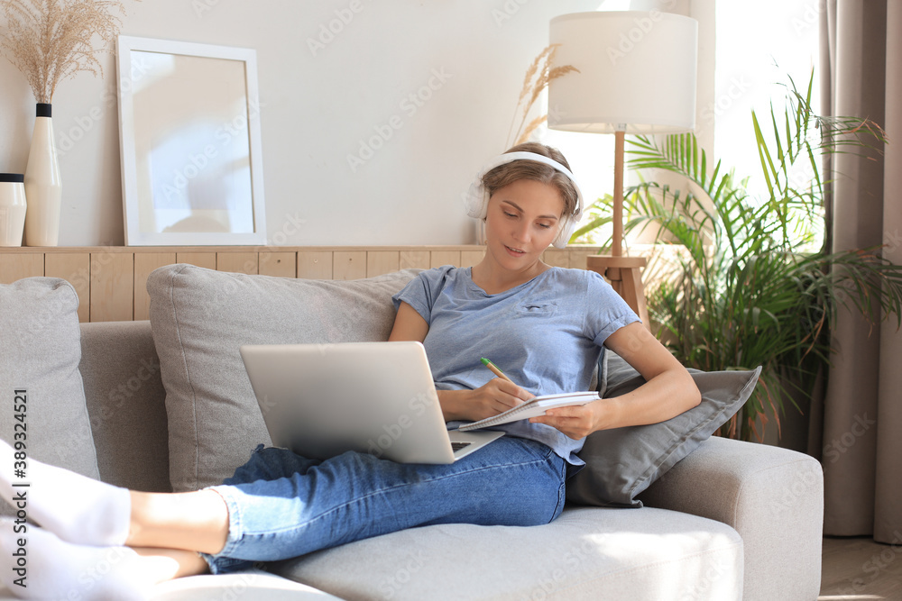 Smiling young woman with headphones and laptop on the sofa. Smiling young woman with headphones and laptop on the sofa.