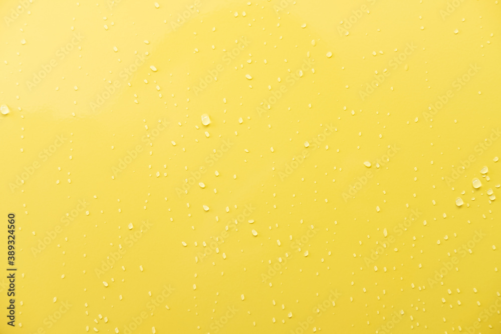 Close up shot of glossy yellow car paint surface. With drop of water and light ambient. Background or wallpaper concept.