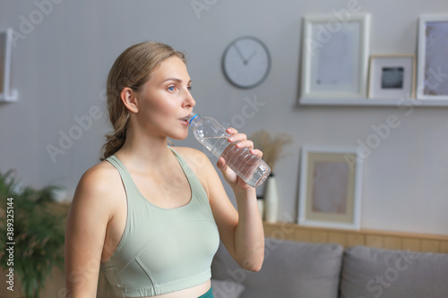 Young beautiful woman drinking water after exercising. Attractive female bodybuilder working out. Fitness and healthy lifestyle concept.