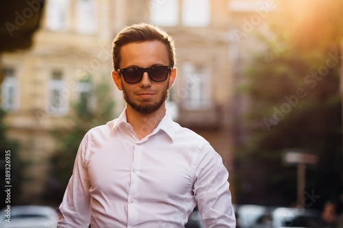 portrait of a young fashion man wearing sunglasses and white shi