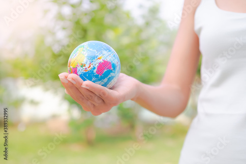 Close up hand woman holding earth on blur image of grass background. Environmental conservation Earth Day concept. copy space.