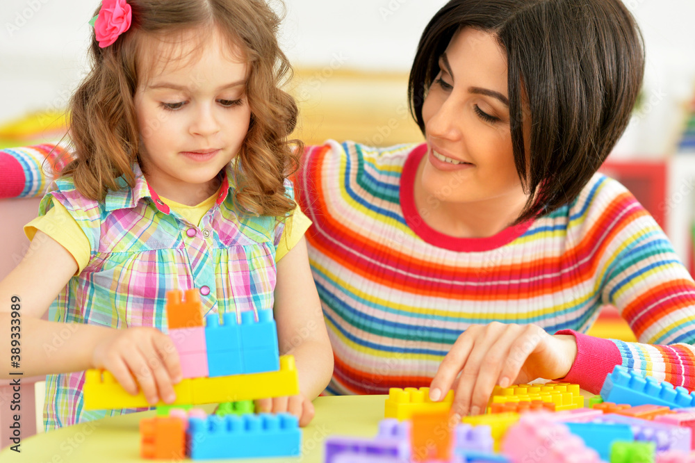 Cute little girl and her mother playing colorful plastic blocks together Cute little girl and her mother playing colorful plastic blocks together