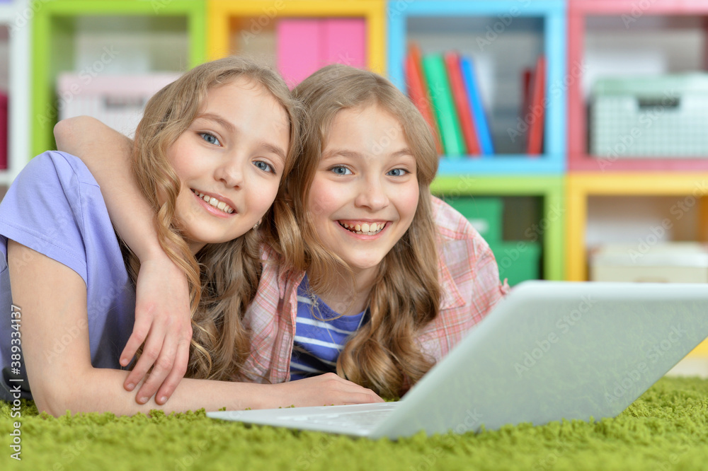 Two pretty little girls lying on floor and using laptop Two pretty little girls lying on floor and using laptop