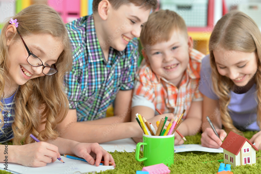 Fototapeta premium Children lying on floor drawing with pencils