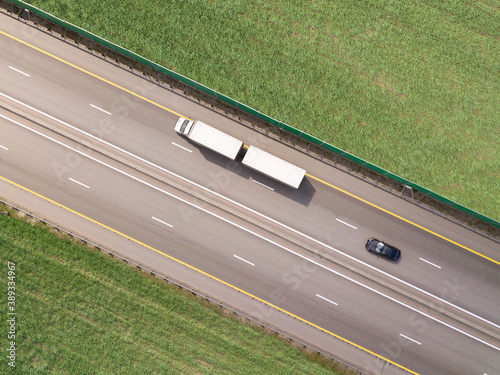 Dump trucks carrying goods on the highway. Red truck driving on asphalt road along the green fields. seen from the air. Aerial view landscape. drone photography. cargo delivery