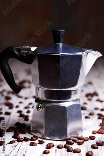 Disassembled metallic geyser coffee pot, coffee maker on white wooden background with coffee beans. Italian coffee pot