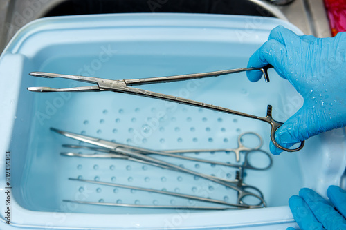 A medical worker rinses surgical instruments in a tray of water. Disinfection of medical equipment