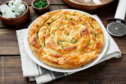 Traditional feta cheese phyllo pastry pie on wooden background .	