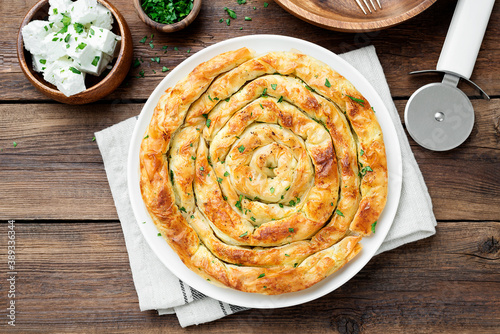 Traditional feta cheese phyllo pastry pie on wooden background .	 photo