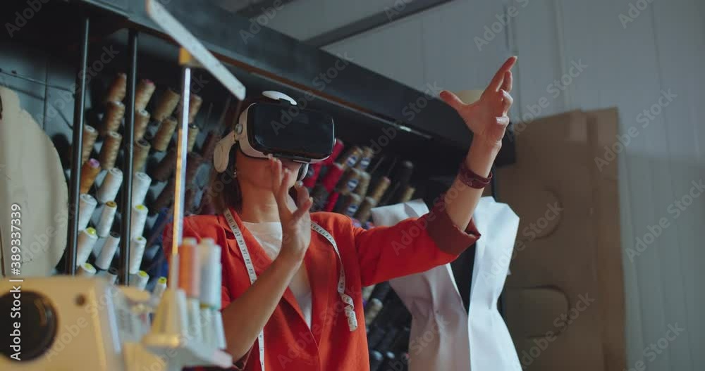 Close up portrait young Caucasian woman designer standing in own studio in VR headset Female couturier in atelier working in virtual reality glasses using futuristic innovations for fashion industry