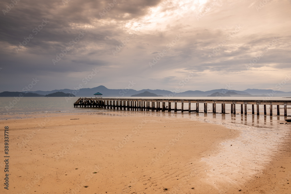 Sunrise or sunset on the sea coast with pier near sea water