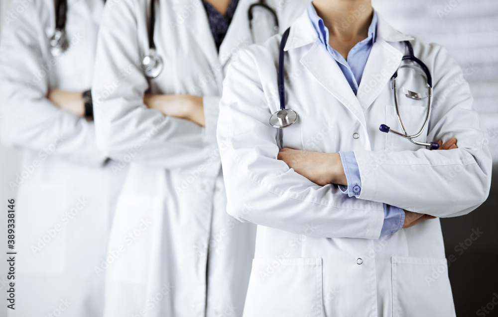 Group of modern doctors standing as a team with arms crossed in hospital office and ready to help patients. Medical help, insurance in health care, best disease treatment and medicine concept Group of modern doctors standing as a team with arms crossed in hospital office and ready to help patients. Medical help, insurance in health care, best disease treatment and medicine concept