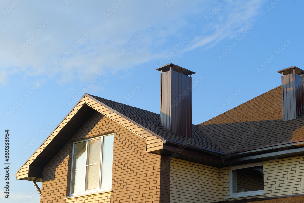 Facade and roof of a brick building against a blue sky