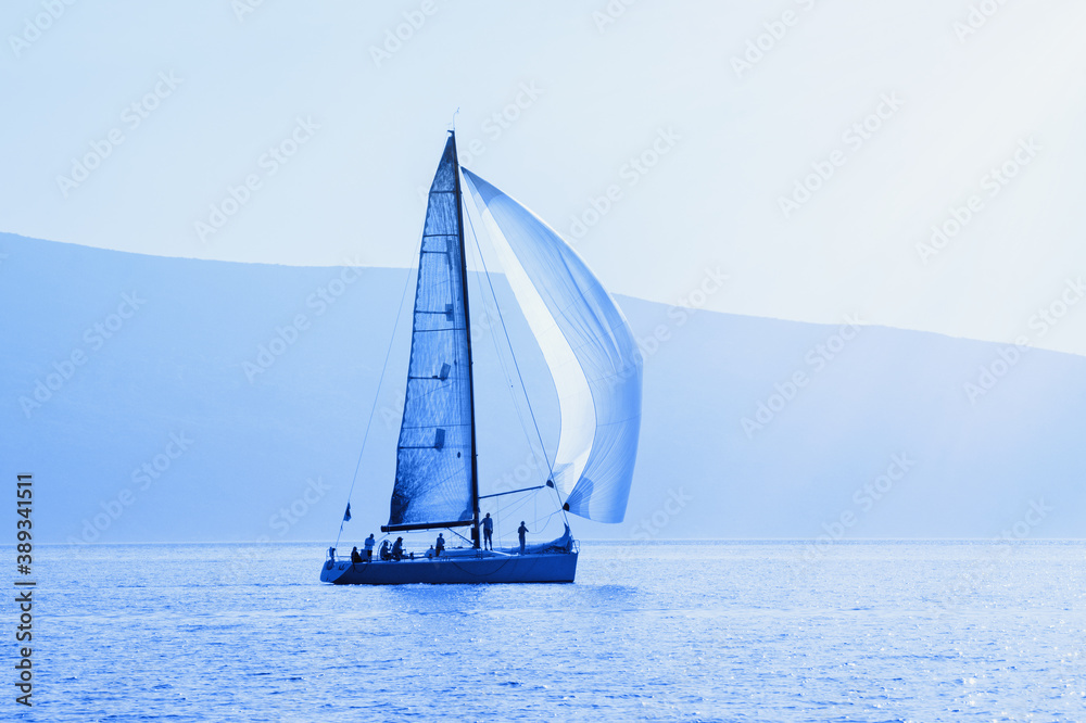 Sailing boat on water, blue tinting, silhouettes. Montenegro, Kotor Bay. Travel concept
