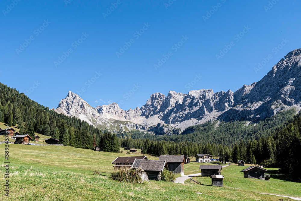 Tal mit Holzhütten im Hintergrund Berge und Bäume in Südtirol