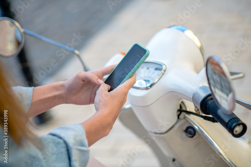 Woman making a stop for texting while riding a scooter