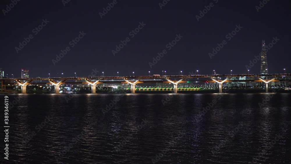 Subway train and many cars moving along the Cheongdam Bridge Over Han River At Night, Lotte Tower In The Background Subway train and many cars moving along the Cheongdam Bridge Over Han River At Night, Lotte Tower In The Background