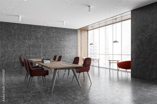 Dark grey office, wooden tables and red chairs on marble floor. Minimalist office room