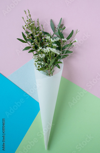 white flowers in paus tracing paper cone on colored paper background