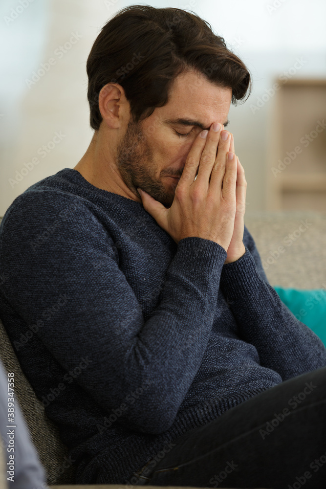 mid adult man with headache on sofa at home mid adult man with headache on sofa at home