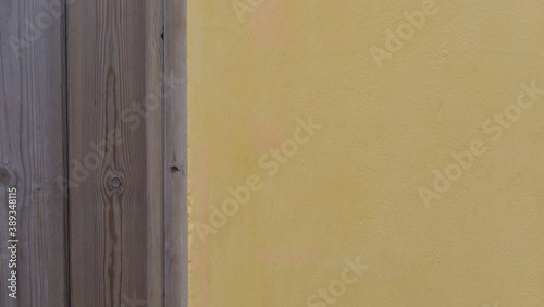 Background comprising vertical wooden planks and yellow plaster with copyspace