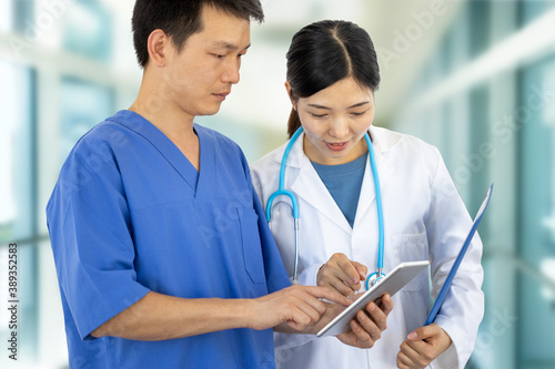 couple of doctors at work with lab coats, stethoscopy and tablet consult each other, concept of professional collaboration between healthcare workers photo