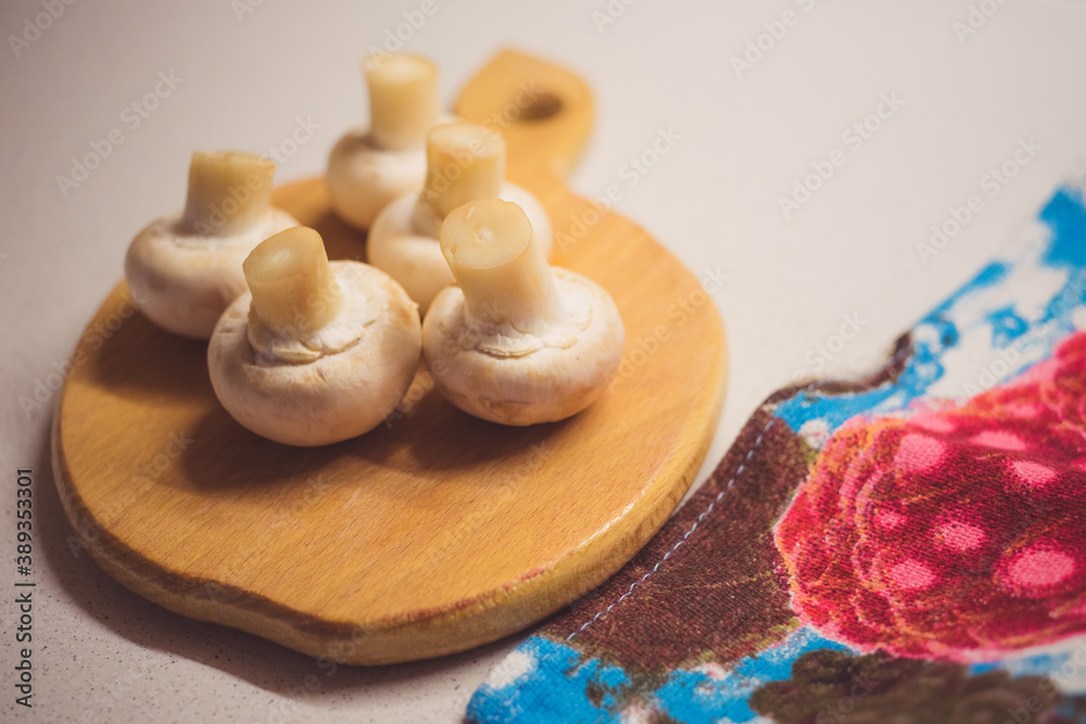Five fresh mushrooms lie on a wooden board with a kitchen towel. Five fresh mushrooms lie on a wooden board with a kitchen towel.