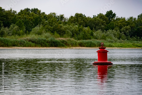 Large metal bright buoy on the river in the Rostov region. Designation of the depth and limit of movement for navigation of water transport, ships and barges with cargo. Russian nature, vegetation and