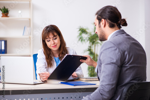 Young female doctor and sick businessman in the office