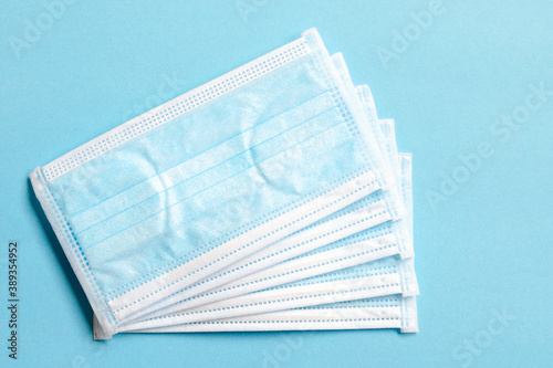 Medical masks on a blue background, top view. Surgical medical mask isolated on blue background. Prevent coronavirus. Medical 3-ply surgical mask to cover the nose and mouth. Disposable medical mask. © aneriksson