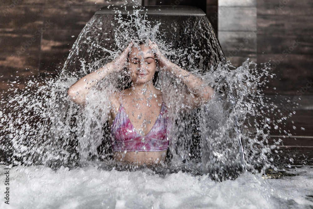 Fototapeta premium Happy woman having fun under waterfall jet