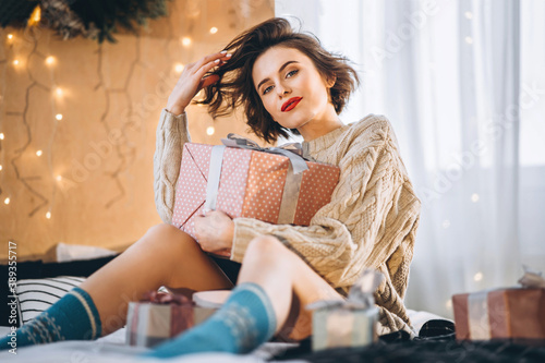 Happy and pretty brunette on the bed with gift boxes around her.
