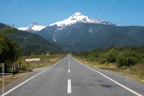 perspective sur route asphaltée en ligne droite avec une montagne enneigée surplombant la scène en arrière plan 