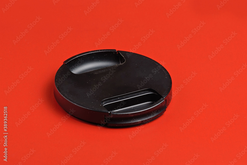Protective cover of the photo lens on a red background close-up Protective cover of the photo lens on a red background close-up