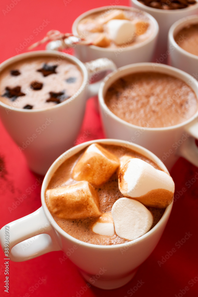 Close-up hot cocoa with marshmallows in white cups on red background, vertical Close-up hot cocoa with marshmallows in white cups on red background, vertical