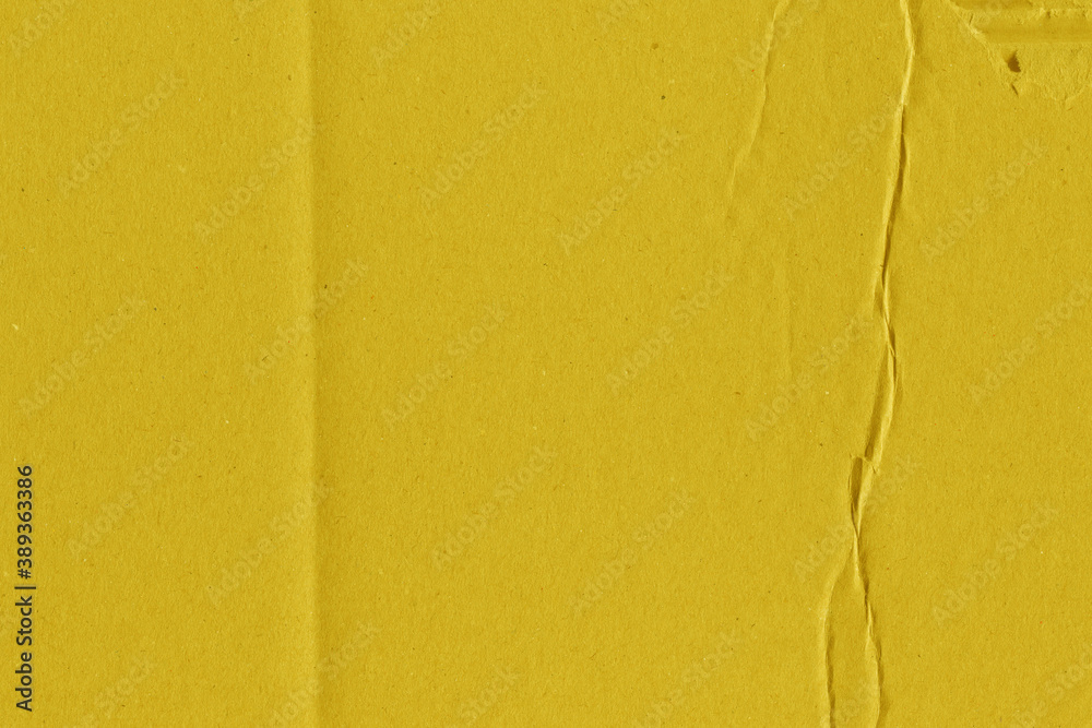 Fototapeta premium A yellow vintage rough sheet of carton. Recycled environmentally friendly cardboard paper texture. Simple and bright minimalist papercraft background.