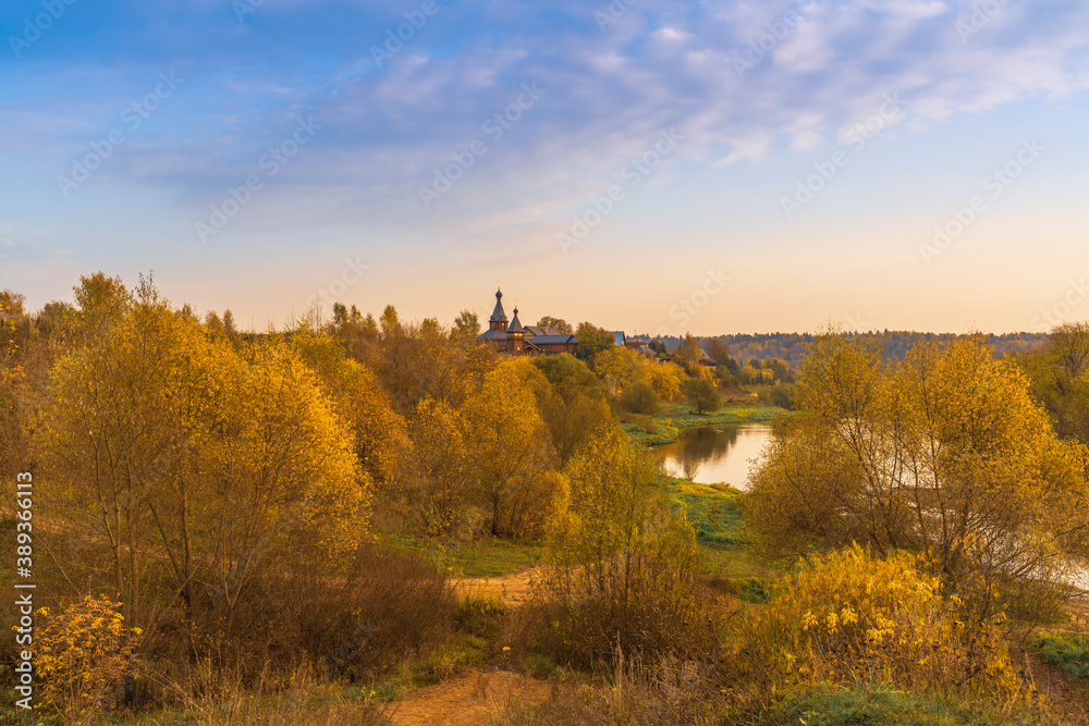 Autumn landscape with river, church and sky in Moscow Region, Russia