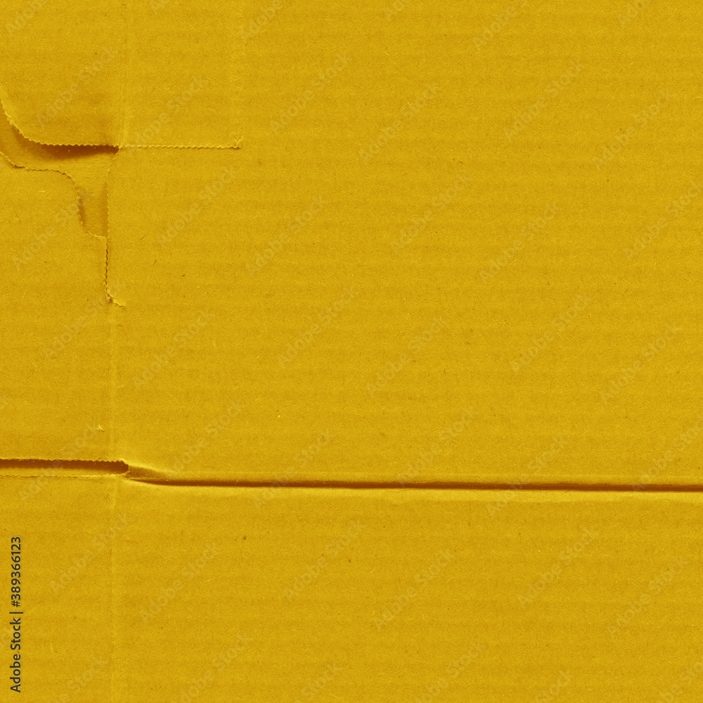 Fototapeta premium A yellow vintage rough sheet of carton. Recycled environmentally friendly cardboard paper texture. Simple and bright minimalist papercraft background.