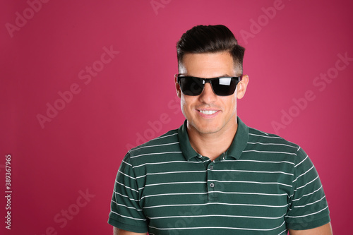 Handsome man wearing sunglasses on pink background