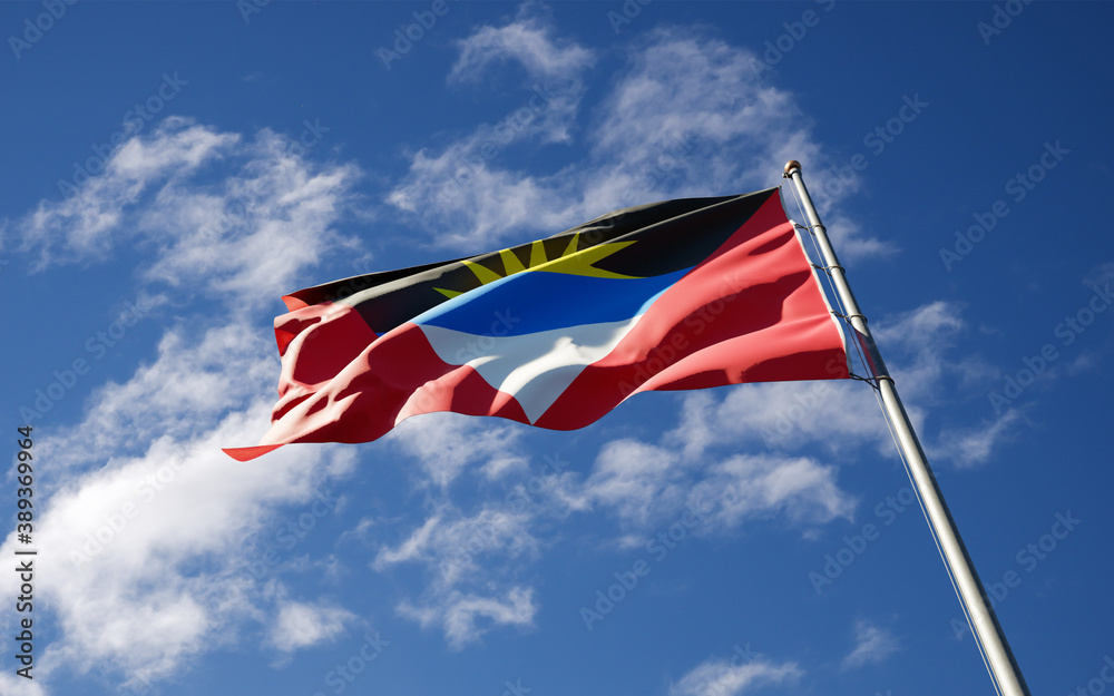 Beautiful national state flag of Antigua and Barbuda fluttering at sky background. Low angle close-up flag 3D artwork.