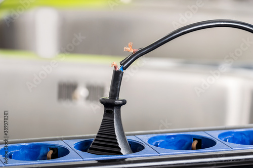 Close up of a dangerous damaged electrical cord a kitchen counter at home photo