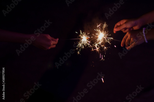 Hand on children holding sparkler playing for fun at night.
