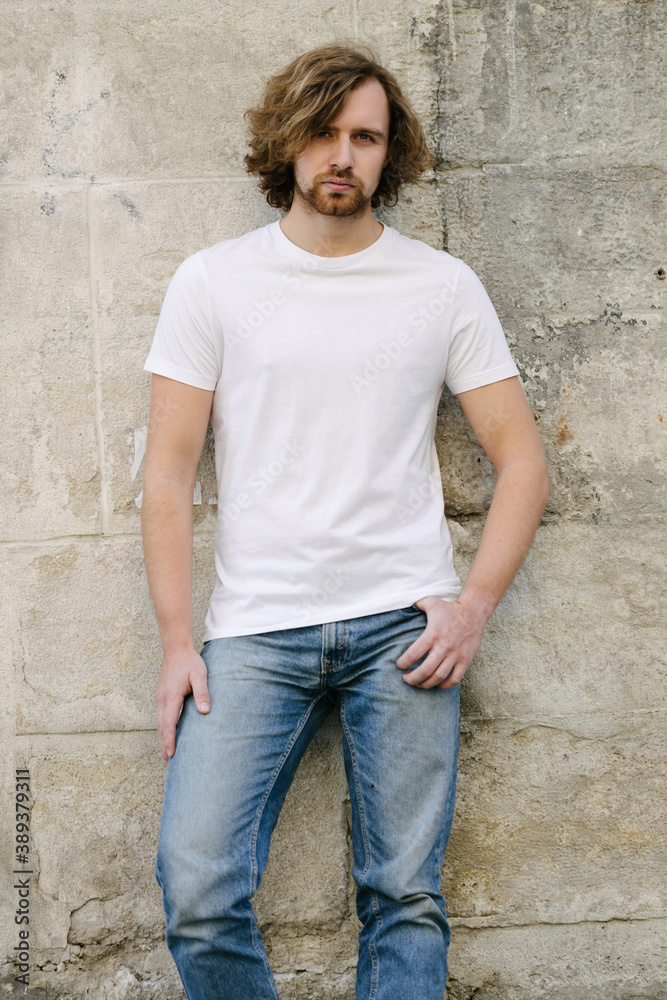 Hipster handsome male model wearing white blank t-shirt with space for your logo or design in casual urban style on europian streets Hipster handsome male model wearing white blank t-shirt with space for your logo or design in casual urban style on europian streets