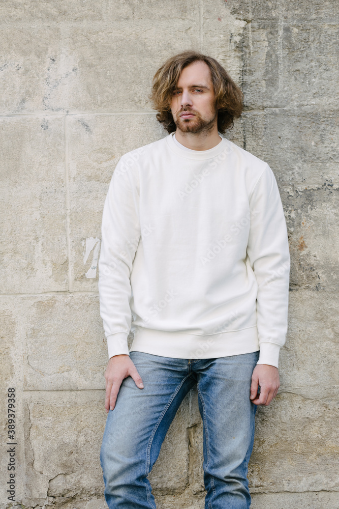 Man wearing white sweatshirt or hoodie for mock up, logo designs or design prints with with free space among europe city streets. Man wearing white sweatshirt or hoodie for mock up, logo designs or design prints with with free space among europe city streets.
