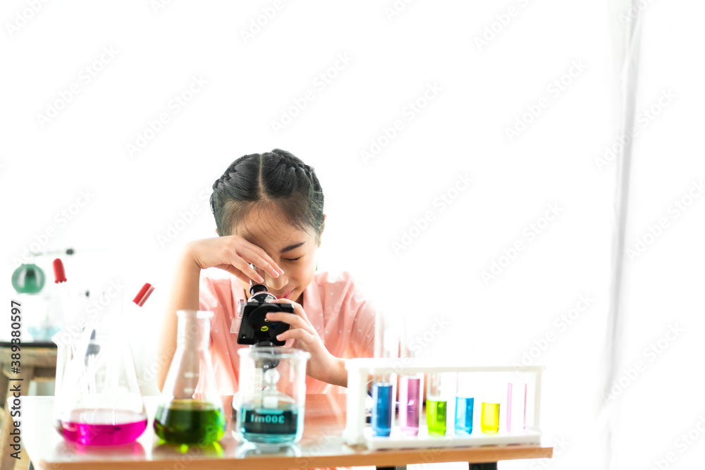 Cute little girl student child learning research and doing a chemical experiment while making analyzing and mixing liquid in glass at science class on the table.Education and science concept Cute little girl student child learning research and doing a chemical experiment while making analyzing and mixing liquid in glass at science class on the table.Education and science concept